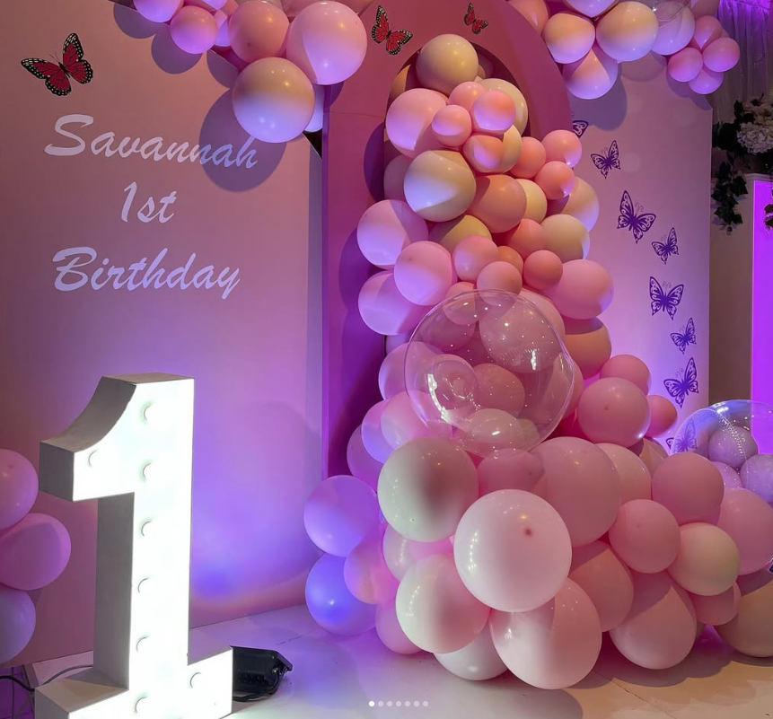 Pink first birthday balloon display with butterflies.