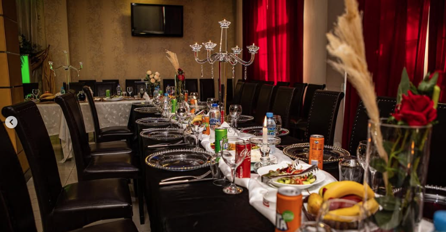 Long dining table set with plates, drinks, flowers, and candles.